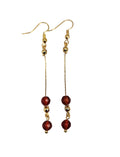 Gold-plated dangle earrings with deep red agate faceted beads on a white background.