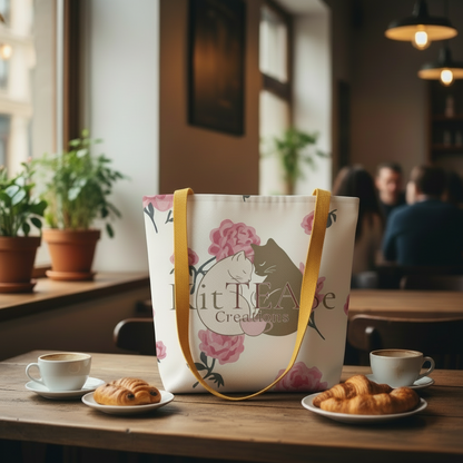 Limited edition KitTEASe Creations tote bag with cat illustration and roses, placed on café table for lifestyle aesthetic
