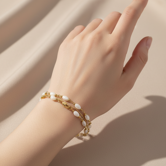 Woman wearing gold plated bracelet with shell and gold beads accents on wrist
